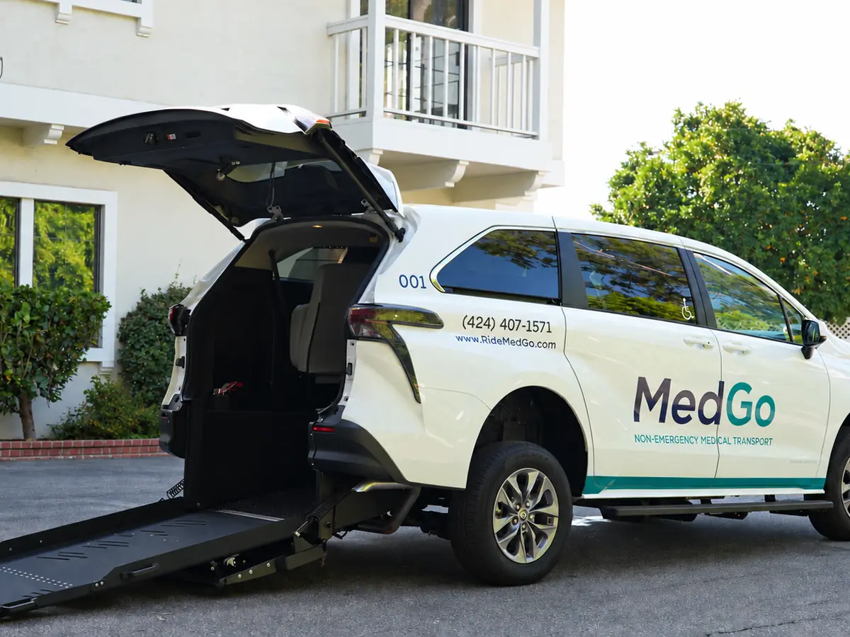 The MedGo Transportation van with its rear ramp lowered outside a building, ready for a wheelchair rider.